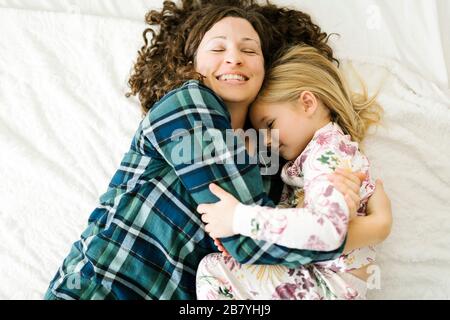 Vista ad alto angolo di madre e figlia in pigiama sdraiato a letto Foto Stock
