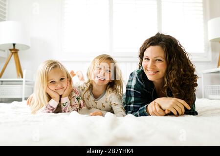 Madre e figlie giacenti a letto in pigiama Foto Stock