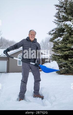 Uomo anziano che tovana la neve Foto Stock