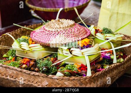 Un cestello archiviato con offerte costituito da fiori in piccolo tessuto cesti parte della vita quotidiana dei rituali di Bali, Indonesia Foto Stock