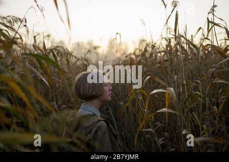 Giovane donna in campo di erba lunga Foto Stock