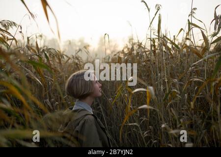 Giovane donna in campo di erba lunga Foto Stock