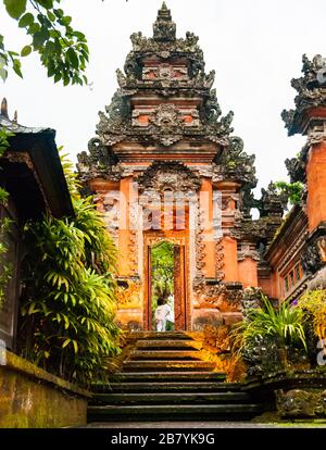 Un giovane bambino passa attraverso un portale in stile tradizionale gate presso il Café Lotus in Ubud, Bali Foto Stock