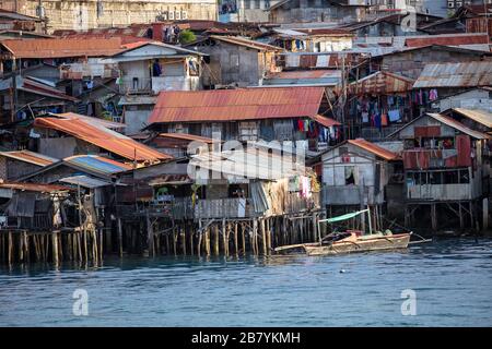 Quartieri poveri baraccopoli con case di legno su acqua, Cebu città, Filippine. Foto Stock