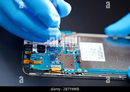 Asian tecnico riparazione circuito micro scheda principale dello smartphone tecnologia elettronica : computer, hardware, telefono cellulare, aggiornamento, concetto di pulizia. Foto Stock