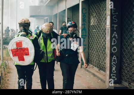 SANTIAGO, CILE-8 NOVEMBRE 2019 - i volontari della Croce Rossa fuggono dal gas lacrimogeno durante le proteste contro il governo di Sebastian Pinera, per il sociale c Foto Stock