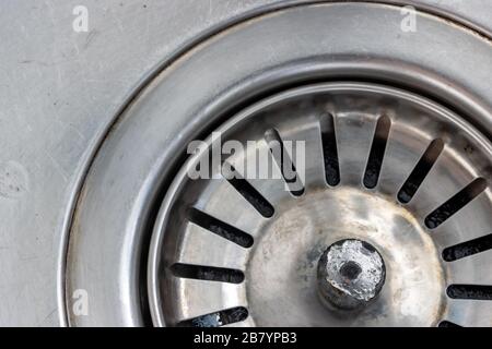 Un lavandino in metallo con foro di scarico, vista macro. Chiusura del tappo di scarico a regolazione meccanica. Foto Stock