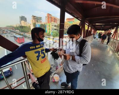 Un cliente che contrattava con un falco di maschera per bye maschera da lui a Banani, Dhaka. A causa del virus Corona, la domanda di maschera è attualmente alla massima richiesta. Foto Stock