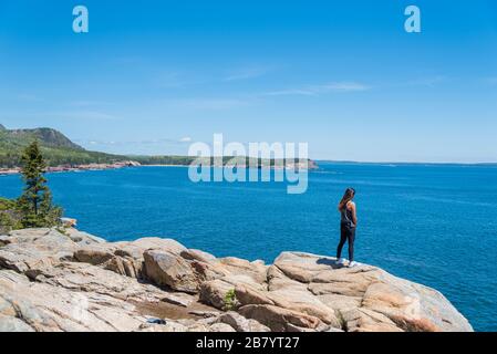 Donna che gode della splendida vista dell'oceano Atlantico dalla costa in Acadia National Park Maine USA Foto Stock