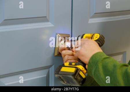 Manuale con un trapano a cacciavite per installare la serratura nella porta in una casa Foto Stock