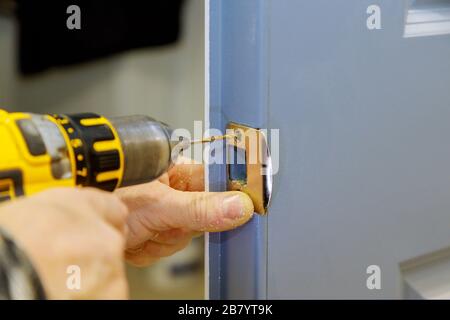 installazione delle mani dei lavoratori nuovo armadietto della portiera nella serratura della portiera Foto Stock