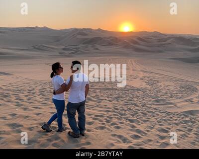 Coppia godendo la vista di un bellissimo tramonto all'Oasi di Huacachina in Perù Foto Stock