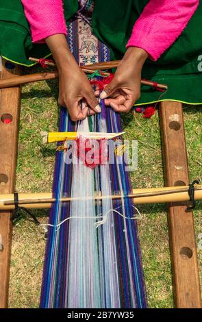 Una donna che tesse un tessuto tradizionale delle Ande fatto a mano nella città di Cusco, Perù. Foto Stock