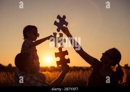 Buona famiglia che gioca al parco all'ora del tramonto. Persone che si divertono sul campo. Il concetto del bambino è pronto per andare a scuola. Foto Stock