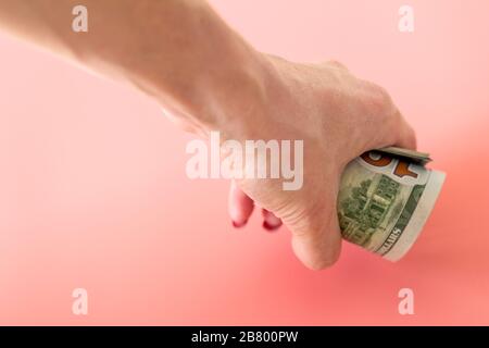 spremuto denaro su donna pugno. mano donna che prende un rotolo di dollari. Foto Stock