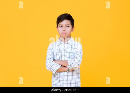 Sulky annoiato ragazzo pouting bocca e pensare con braccio attraversato gesto isolato sfondo giallo Foto Stock