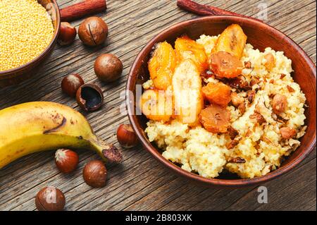 Porridge di miglio dolce con banane e noci in ciotola di ceramica. Foto Stock