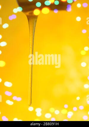 Schizzi di miele dolce biologico. Miele che sgocciola con miele penetratore. Il miele scorre dal bilanciere. Miele che si immerge dal cucchiaio di miele di legno Foto Stock
