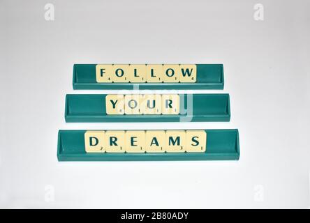 Le tessere di Scrabble incantano fuori segua i vostri sogni. Citazione motivazionale blocchi Scrabble lettere Grigio sfondo citazione di vita indurre alfabeto. Foto Stock