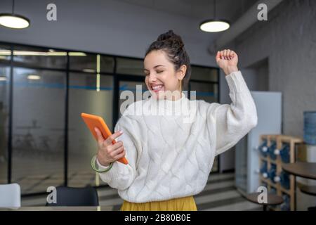 Giovane donna che guarda il tablet con il braccio sollevato Foto Stock