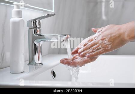 Donna giovane lavando le mani con sapone in bagno, vista ravvicinata. Foto Stock