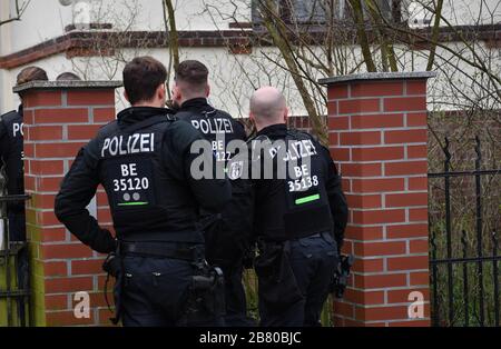 Berlino, Germania. 19 Mar 2020. Gli agenti di polizia sono in piedi ad un cancello ad una casa durante un raid appartamento. Dopo il divieto del gruppo dei cittadini del Reich "popoli e tribù della Germania unita", le incursioni si sono svolte in diversi stati. Credit: Paul Zinken/dpa-Zentralbild/dpa/Alamy Live News Foto Stock