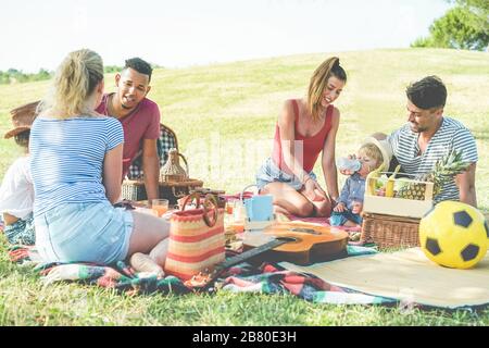 Famiglie felici fare pic-nic nel parco naturale all'aperto - giovani genitori che si divertono con i bambini in estate mangiare e ridere insieme - positivo moo Foto Stock