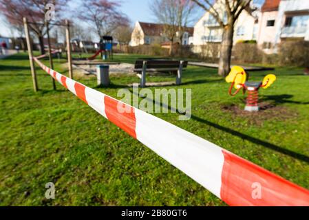 Rot-weisses Absperrband an einem gesperrten Kinderspielplatz während der Corona-Krise in Deutschland Foto Stock