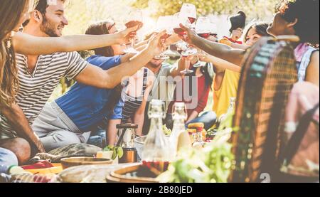 Amici felici che si rallegrano con i bicchieri di vino al picnic cena all'aperto - giovani studenti che si divertono al barbecue in vigna cantina - cibo, stile di vita estivo e y Foto Stock