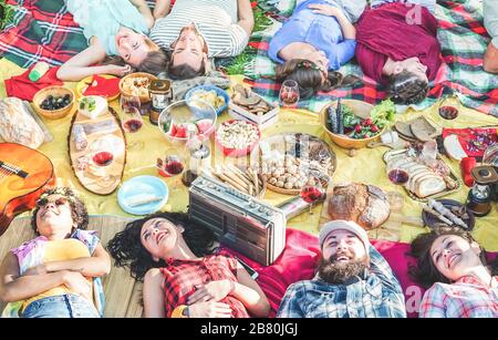 Vista dall'alto amici felici al picnic in campagna - gente alla moda che si diverte mangiare pranzo e bere vino all'aperto - Focus sui ragazzi di fondo facce Foto Stock