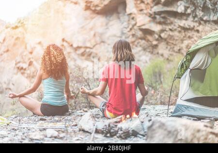 Coppia di escursionisti meditating prima di cena all'aperto - arrampicatori campeggio in montagna rocce e facendo yoga al tramonto - Focus principale su di lui - Viaggi, zen, ESP Foto Stock