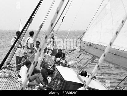 Equipaggio e afterguard a bordo di uno yacht di classe J 'Velsheda' dopo la prima rimpiazzo, navigando nel Solent, Hampshire, Inghilterra, Regno Unito, estate 1991. Archivia la fotografia di film in bianco e nero Foto Stock