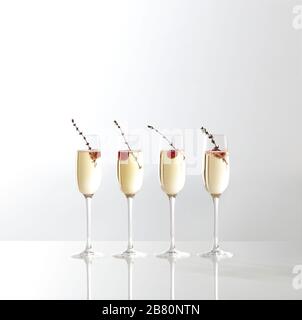 Champagne servito in quattro bicchieri con lamponi sul tavolo Foto Stock