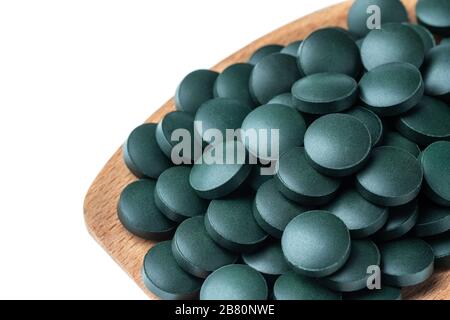 Integratori vitaminici e minerali per vegetariani spirulina in compresse in un cucchiaio di legno, primo piano Foto Stock