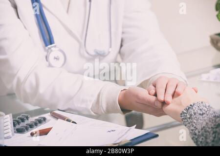il medico della donna tiene la mano del suo paziente per dare il suo sostegno e la compassione Foto Stock