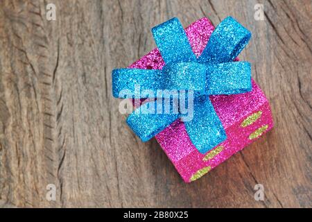 Scatola regalo di Natale con arco blu su un primo piano in tessuto di legno. Foto Stock