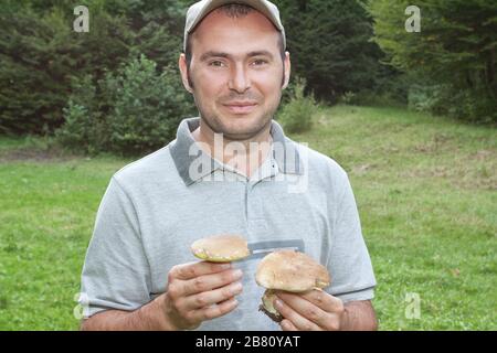 Il tipo che tiene i funghi nella foresta. Foto Stock