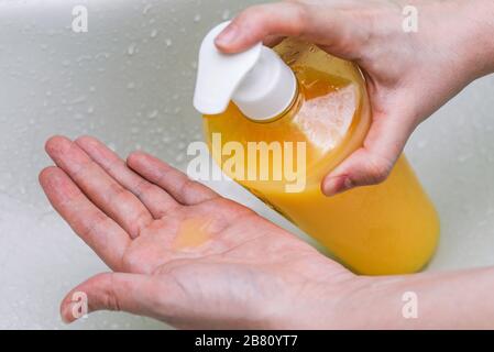 Sapone per il lavaggio delle mani. Le mani femminili contengono un flacone con sapone antibatterico liquido. Detergente per la rimozione di batteri e virus dalla pelle. Foto Stock