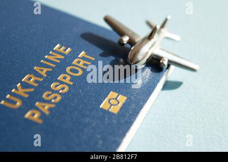 Passaporto ucraino straniero con figura di metallo di piccolo aeroplano su sfondo blu chiaro e soleggiato. Foto concettuale trendy di viaggi e aviazione Foto Stock