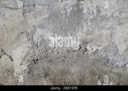 Primo piano di una parete intonacata. Superficie della parete grigio chiaro, ruvida e incrinata. Foto Stock