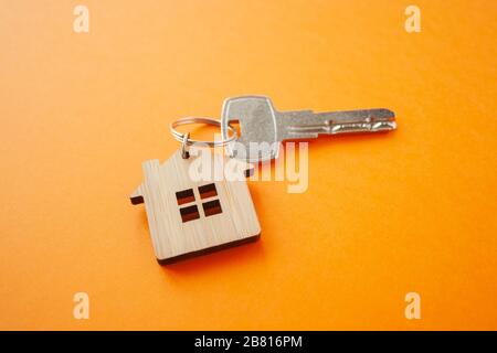 Disposizione portachiavi a forma di chiave e di casa su sfondo arancione. Vista dall'alto, disposizione piatta. Immobiliare, concetto di assicurazione, ipoteca, comprare vendere casa, realtor Foto Stock