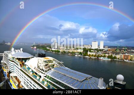 Arcobaleno sulla città di Rotterdam, Paesi Bassi, con la nave da crociera ormeggiata di fronte Foto Stock