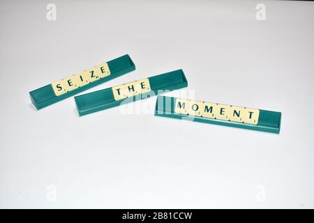 Le mattonelle di Scrabble spell out Seize the Moment citazione di Motivational blocchi di Scrabble lettere grigio sfondo citazione di vita indurre l'alfabeto. Foto Stock