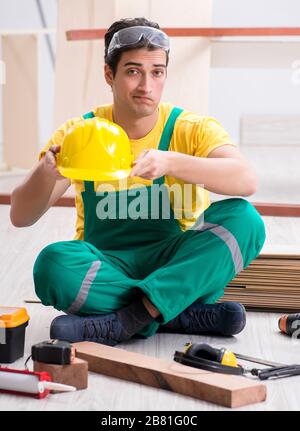 Carpenter indossando giallo hardhat contraente in officina Foto Stock