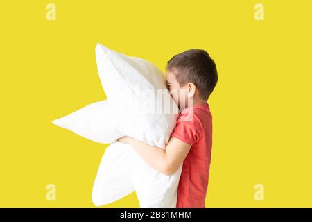 un ragazzo con due cuscini, disturbi del sonno, concetto di sonno per bambini, sfondo giallo Foto Stock