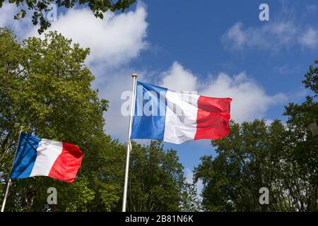 Due bandiere francesi che sventolano al vento, 8 mai, giorno della vittoria, cielo blu Foto Stock