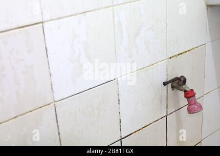 vecchio rubinetto d'acqua in bagno vecchio rubinetto su una parete del bagno Foto Stock