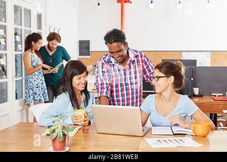 Il team di startup aziendale lavora insieme su un computer portatile nello spazio di lavoro Foto Stock