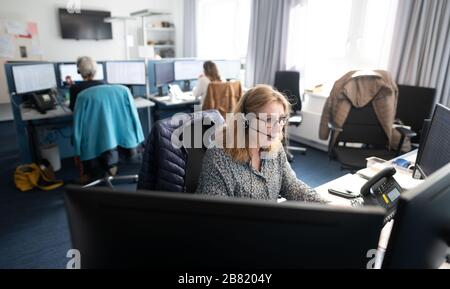 Amburgo, Germania. 19 Mar 2020. Una donna effettua una chiamata telefonica in un centralino telefonico del servizio di guardia del Kassenärztliche Vereinigung Hamburg per il medico hotline '116117' del servizio medico di guardia. Un portavoce dell'Agenzia tedesca per la stampa ha detto che mercoledì si è verificato un calo di oltre 18,000 richieste per la prima volta in cinque giorni. Credit: Daniel Reinhardt/dpa/Alamy Live News Foto Stock