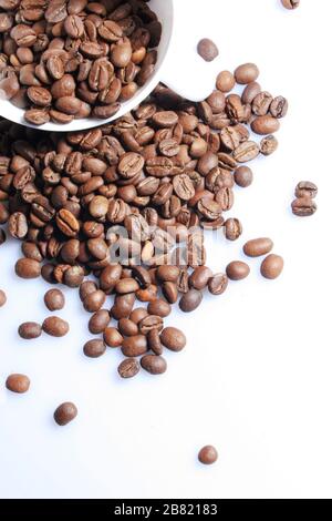 Le tazze bianche riempite con chicchi di caffè fresco hanno uno sfondo bianco. Isolato. Foto Stock